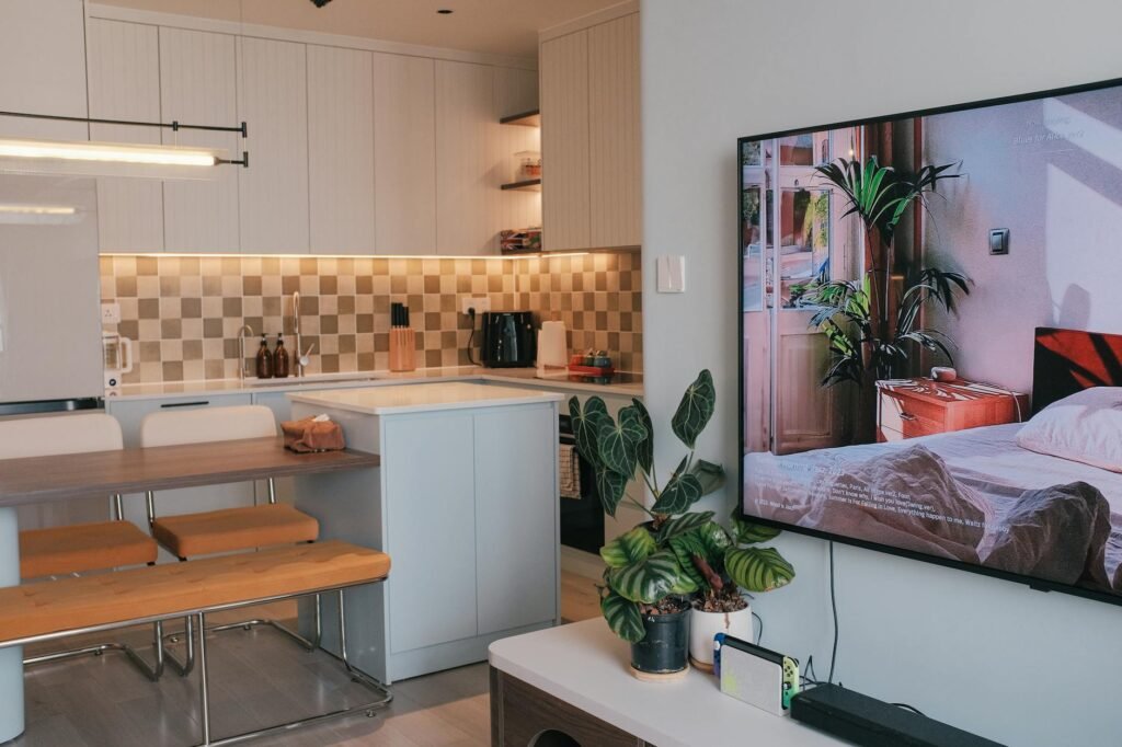 A compact grow light hanging above several indoor plants in an apartment corner