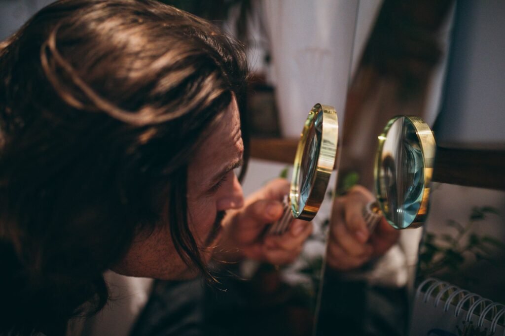 A person inspecting the underside of a houseplant leaf with a magnifying lens